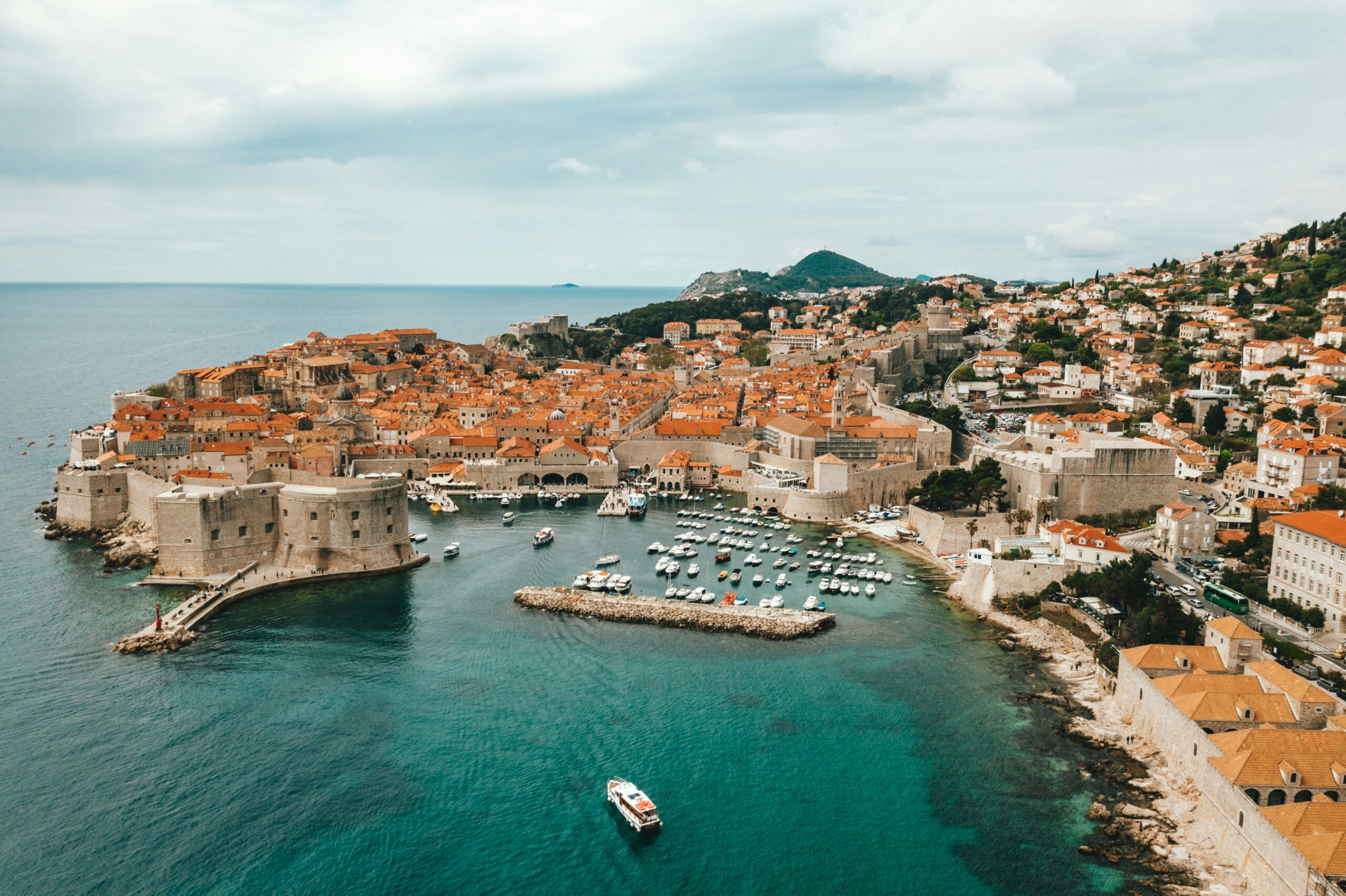 Brač villa management Zračni pogled na povijesni Stari Grad Dubrovnika s lukom, okružen srednjovjekovnim zidinama, uz plavo more u pozadini.